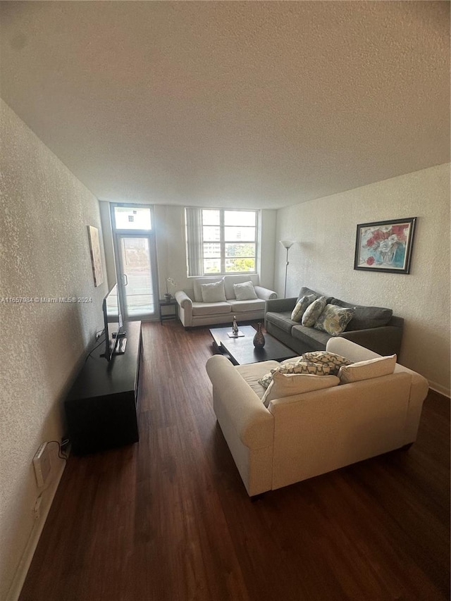 living room featuring dark wood-type flooring and a textured ceiling