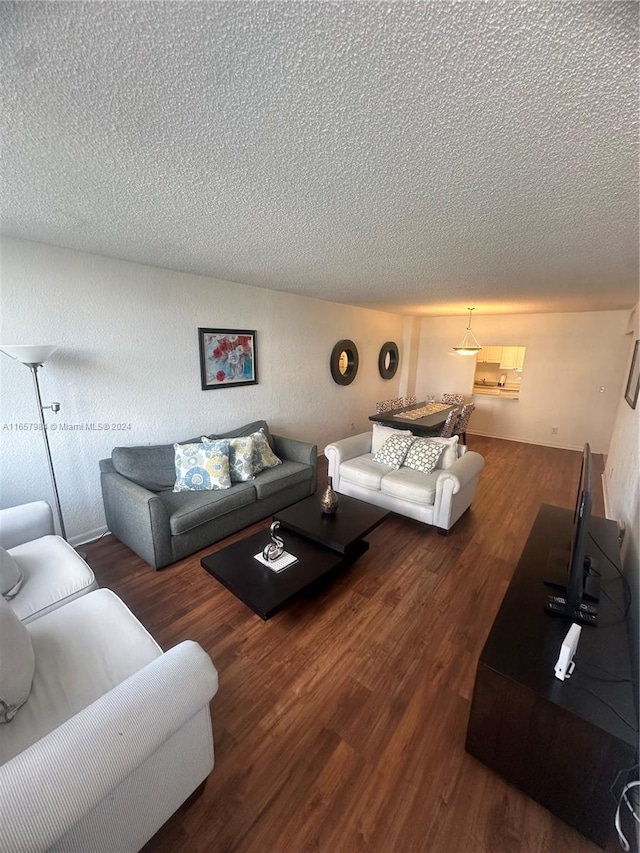 living room featuring a textured ceiling and dark wood-type flooring