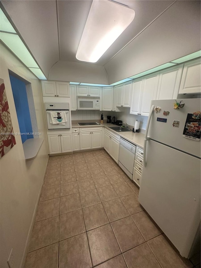 kitchen with white appliances, light tile patterned flooring, lofted ceiling, and white cabinets