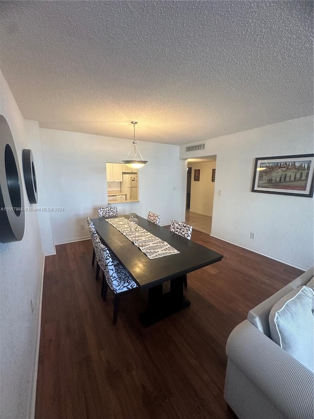 dining space featuring a textured ceiling and dark hardwood / wood-style floors