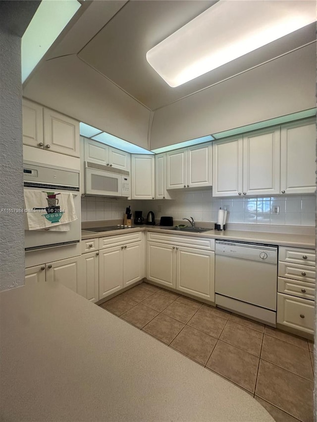 kitchen featuring white appliances, light tile patterned floors, white cabinetry, and sink