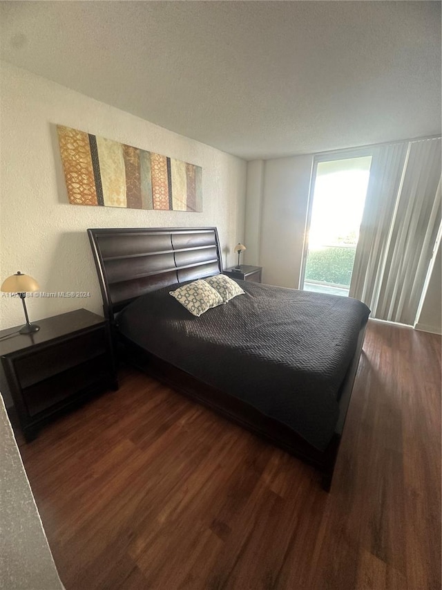 bedroom with a textured ceiling and dark hardwood / wood-style flooring