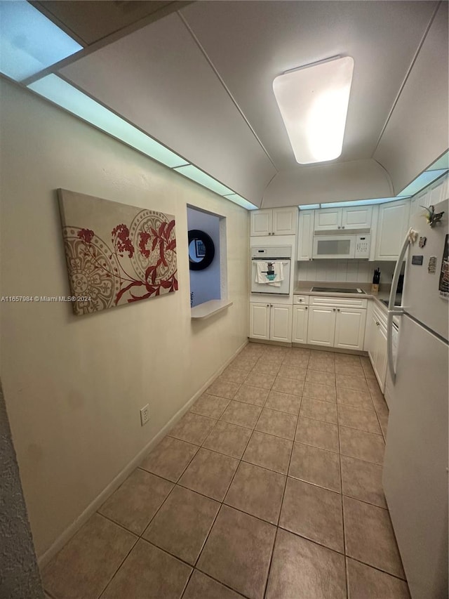 kitchen featuring lofted ceiling, white cabinetry, light tile patterned flooring, and white appliances