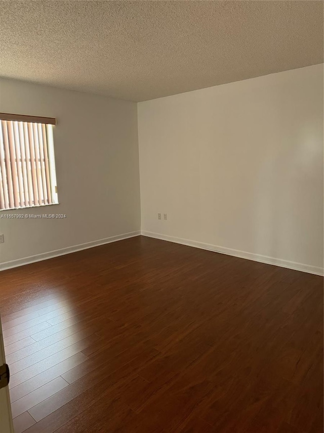 unfurnished room featuring a textured ceiling and dark wood-type flooring