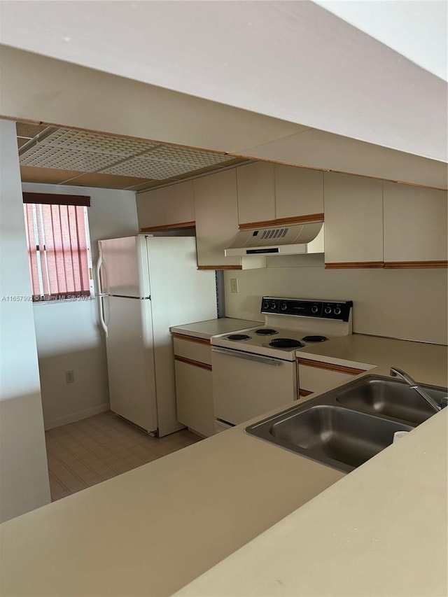 kitchen featuring a sink, baseboards, white appliances, light countertops, and under cabinet range hood