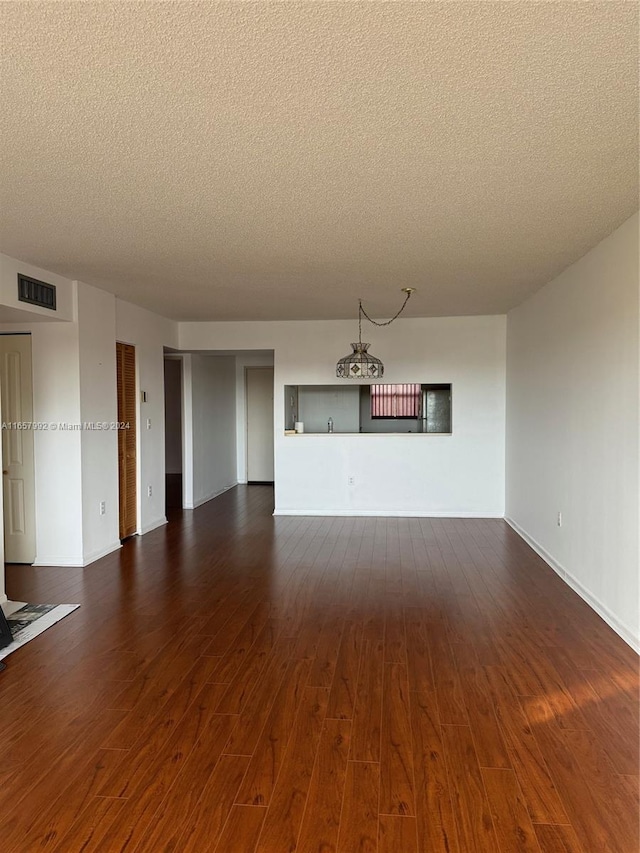 unfurnished living room with dark wood-type flooring and a textured ceiling