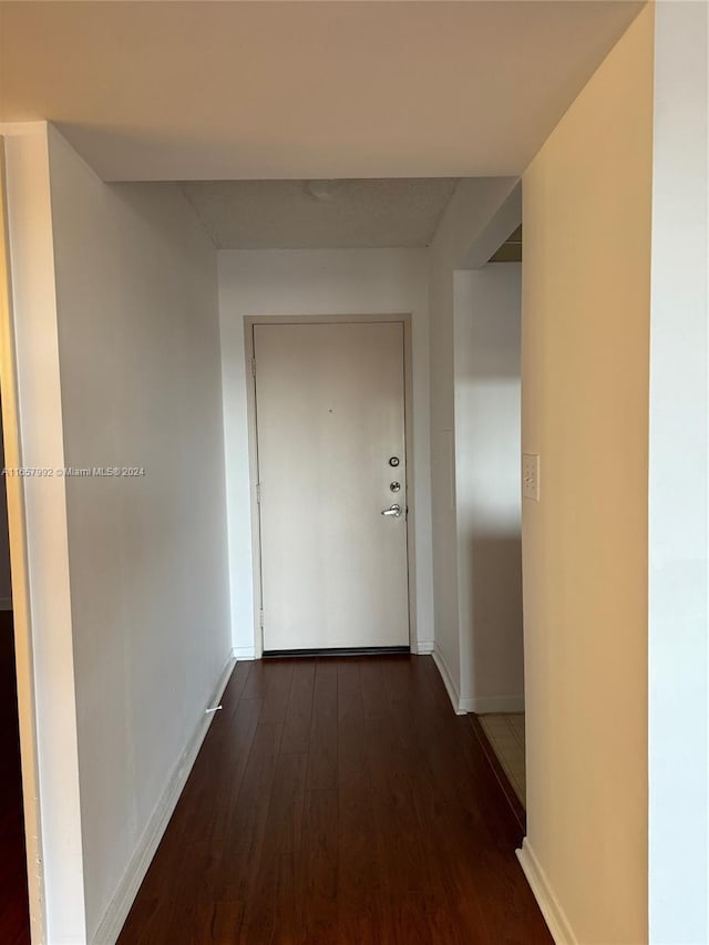 hallway with dark wood finished floors and baseboards