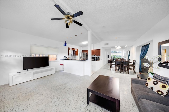 living room featuring lofted ceiling, ceiling fan, and a textured ceiling