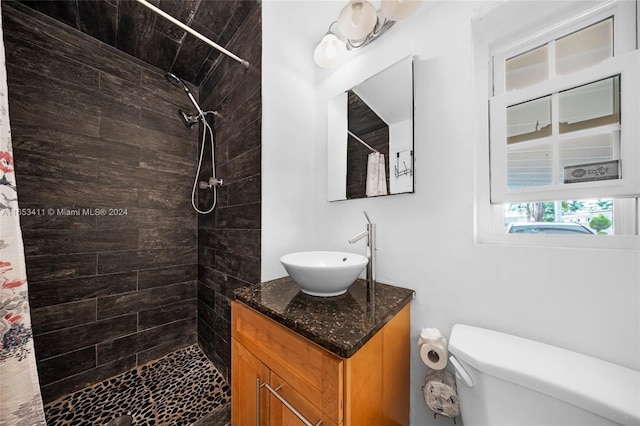 bathroom featuring toilet, vanity, and tiled shower