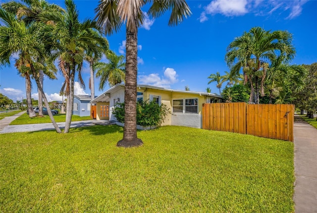 view of front of property featuring stucco siding, concrete driveway, a front lawn, and fence