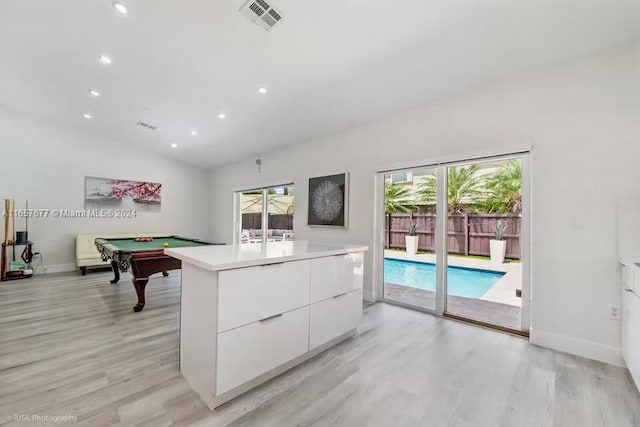 interior space with pool table, a wealth of natural light, white cabinetry, and vaulted ceiling