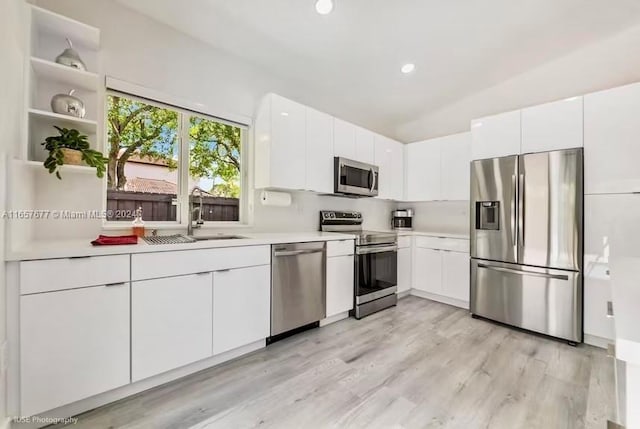 kitchen featuring stainless steel appliances, sink, white cabinetry, and light hardwood / wood-style floors