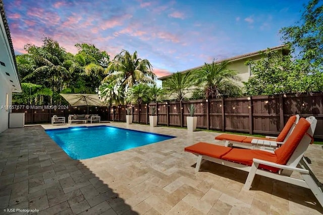 pool at dusk featuring a patio area