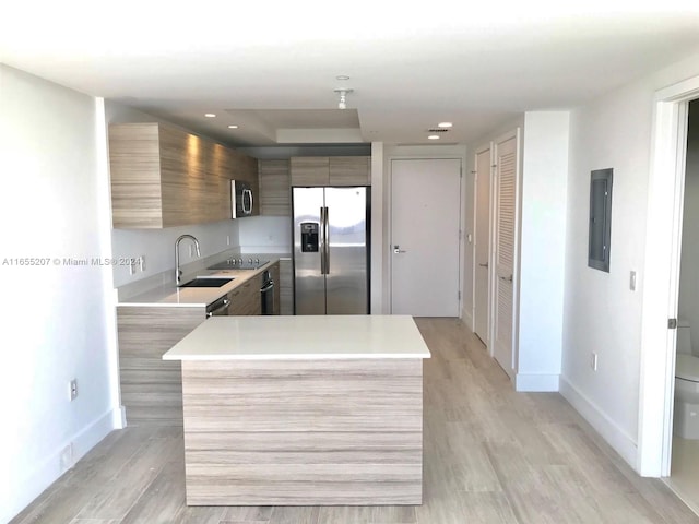 kitchen with light hardwood / wood-style flooring, electric panel, stainless steel appliances, and sink