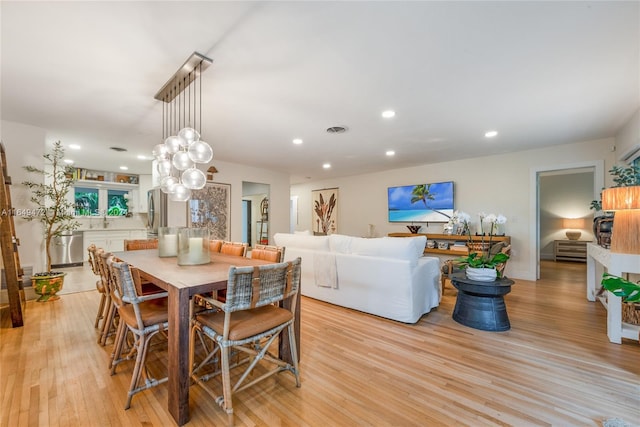 dining room with light hardwood / wood-style flooring and a chandelier