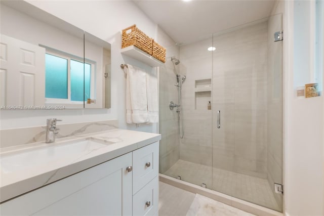 bathroom featuring a shower with door and vanity