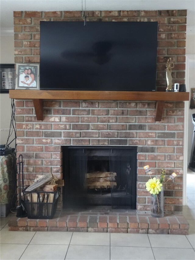 living room featuring ceiling fan, a brick fireplace, a textured ceiling, light tile patterned flooring, and ornamental molding