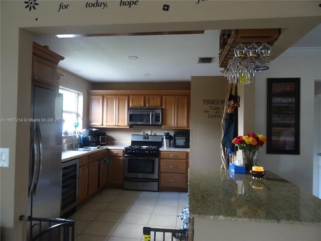 kitchen with kitchen peninsula, light stone countertops, wine cooler, light tile patterned floors, and appliances with stainless steel finishes