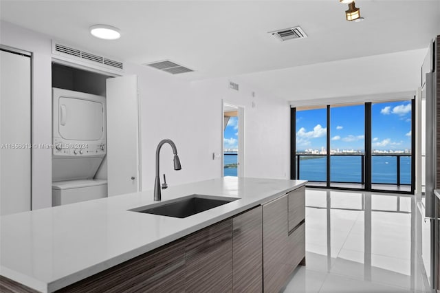 kitchen with a sink, visible vents, and stacked washer and dryer