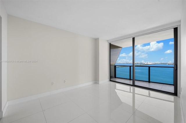 tiled empty room featuring baseboards and expansive windows