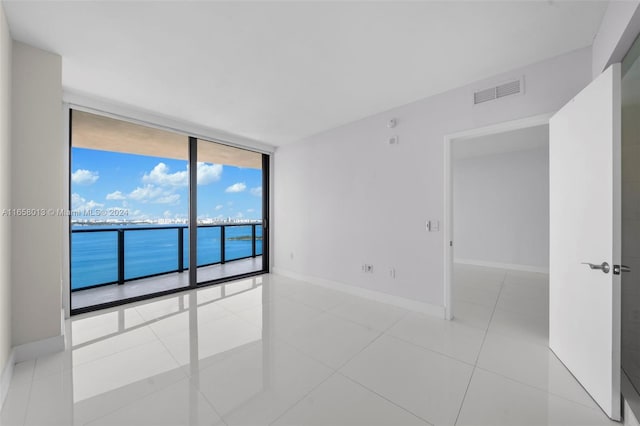 spare room with light tile patterned floors, visible vents, baseboards, and floor to ceiling windows