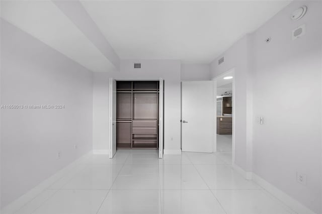 unfurnished bedroom with light tile patterned floors, baseboards, visible vents, and a closet