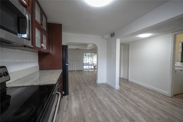 kitchen featuring black appliances, light stone counters, washer / dryer, and light hardwood / wood-style flooring