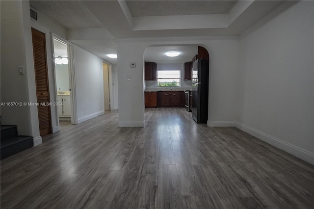 unfurnished living room with a tray ceiling, sink, dark wood-type flooring, and a textured ceiling