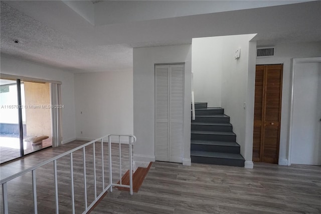 staircase featuring wood-type flooring and a textured ceiling