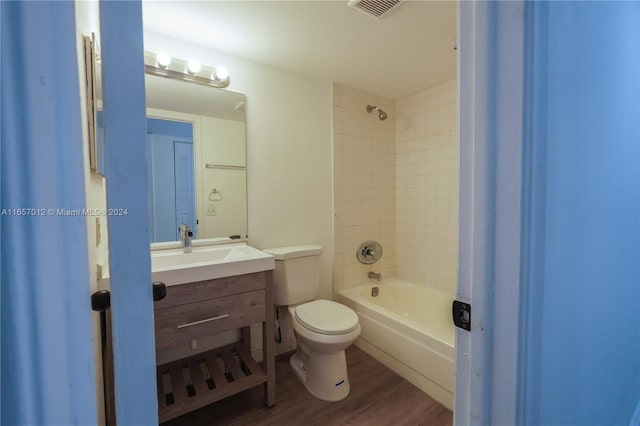 full bathroom with hardwood / wood-style floors, tiled shower / bath combo, toilet, and vanity