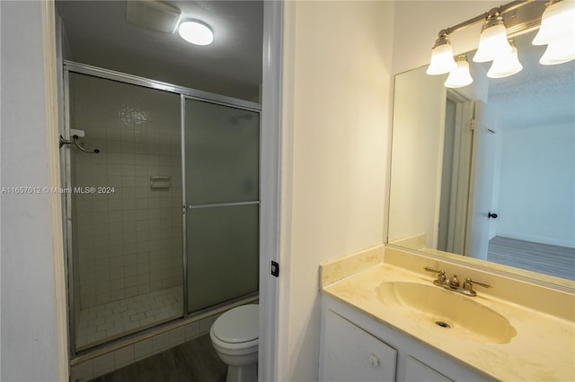 bathroom featuring walk in shower, hardwood / wood-style flooring, vanity, and toilet