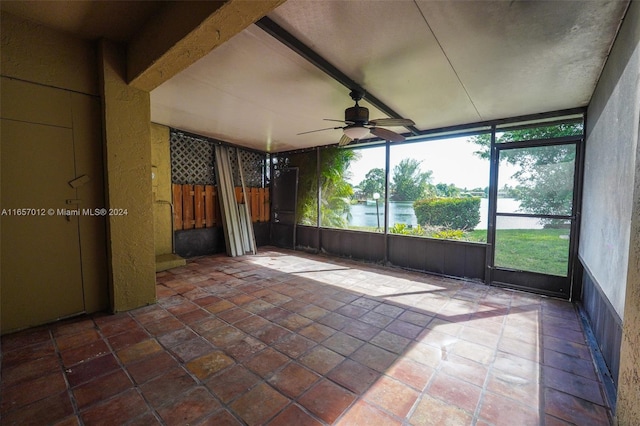 unfurnished sunroom featuring beamed ceiling, a water view, and ceiling fan