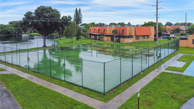 exterior space with a lawn, a water view, and tennis court