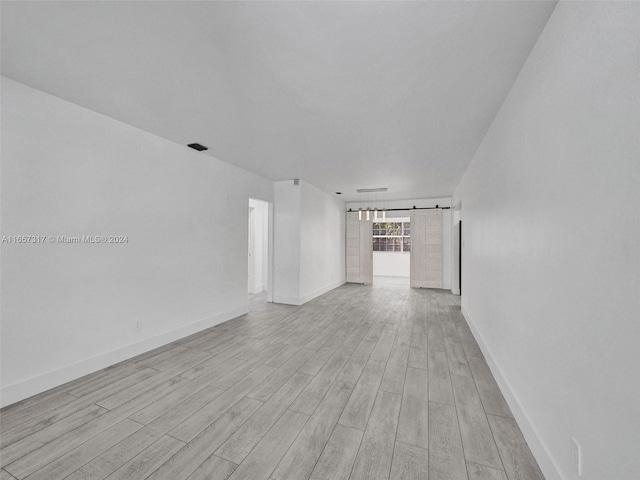 unfurnished living room featuring a barn door and light wood-type flooring