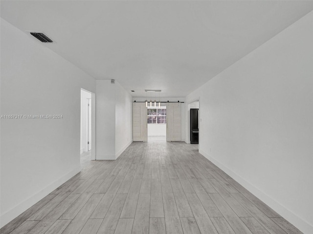 unfurnished room featuring a barn door and light hardwood / wood-style flooring