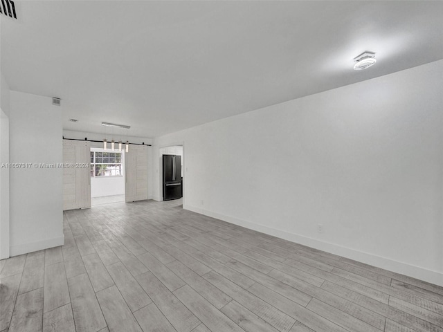 spare room with light hardwood / wood-style flooring and a barn door