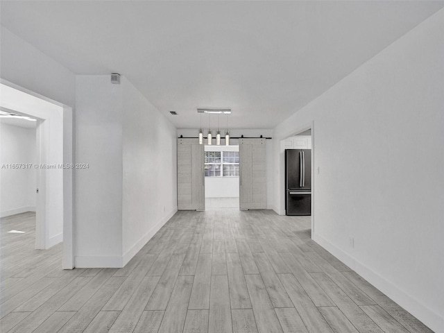 empty room featuring a barn door and light hardwood / wood-style floors