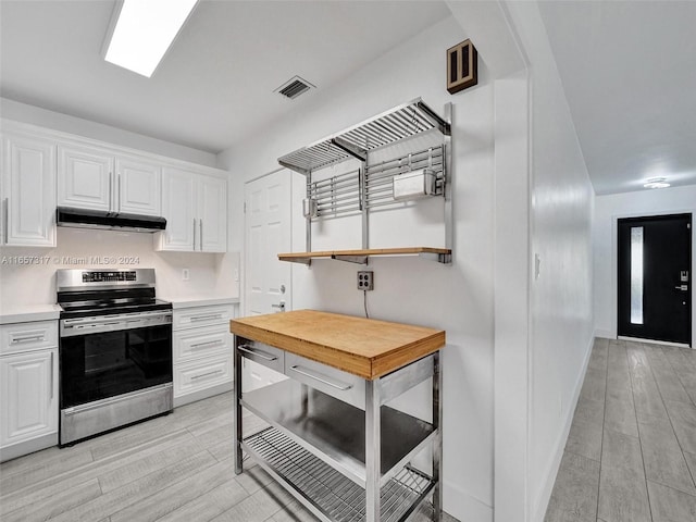 kitchen featuring light wood-type flooring, stainless steel range oven, and white cabinets