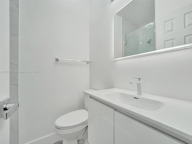 bathroom featuring toilet, a tile shower, and vanity