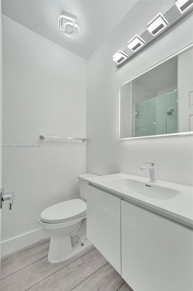 bathroom featuring vanity, toilet, hardwood / wood-style floors, and a shower