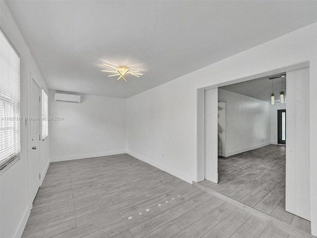 unfurnished room with a wall mounted AC and light wood-type flooring