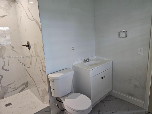 bathroom with toilet, vanity, and a tile shower