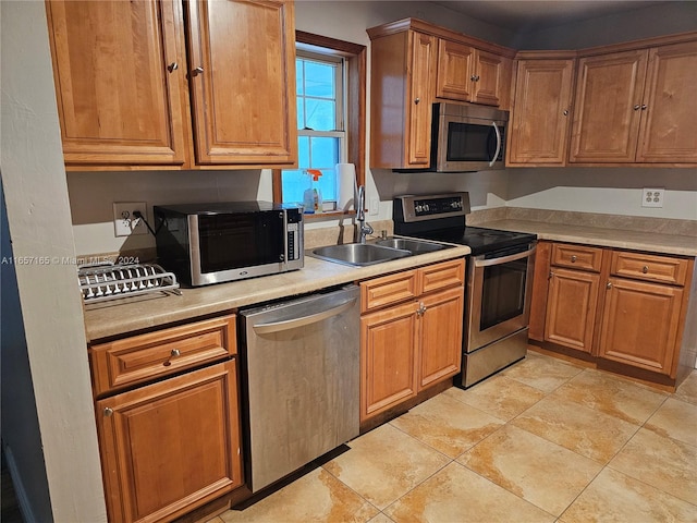 kitchen with appliances with stainless steel finishes, sink, and light tile patterned floors