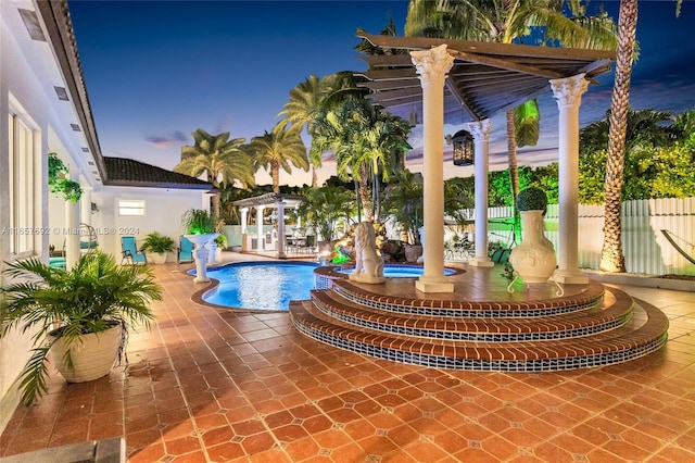 pool at dusk with a patio and a pergola