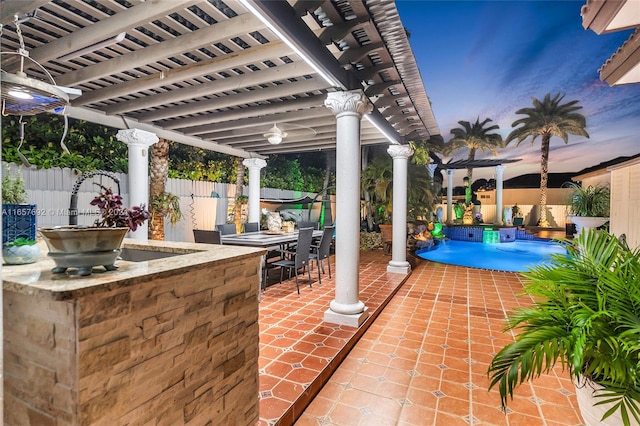 patio terrace at dusk featuring a pergola and a wet bar