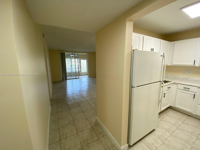 kitchen with white cabinetry, light tile patterned flooring, and white fridge