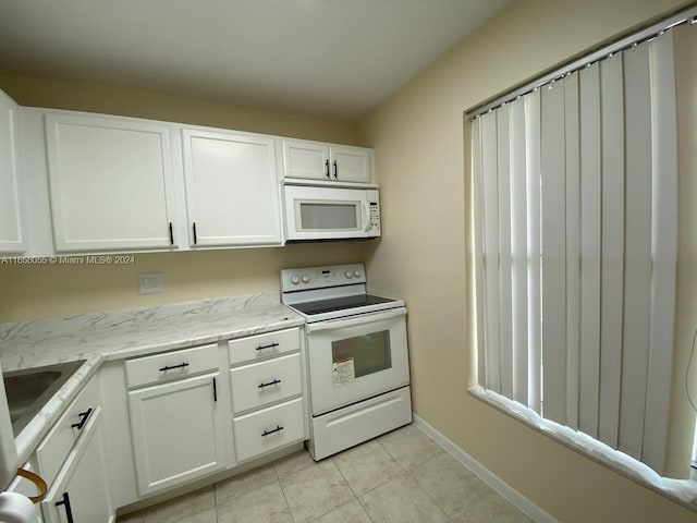 kitchen featuring light stone countertops, white appliances, white cabinetry, and light tile patterned flooring