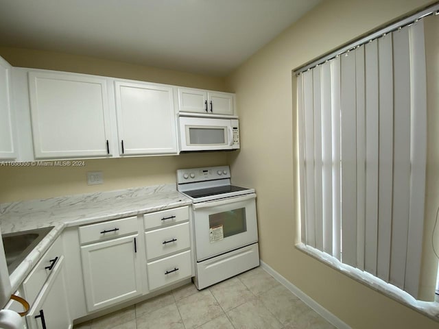 6071 NW 61st Ave Unit 107, Tamarac, FL 33319 - kitchen with white appliances, white cabinets, light tile patterned floors, baseboards, and a sink