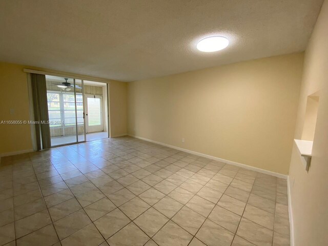6071 NW 61st Ave Unit 107, Tamarac, FL 33319 - spare room featuring light tile patterned floors, a textured ceiling, and baseboards