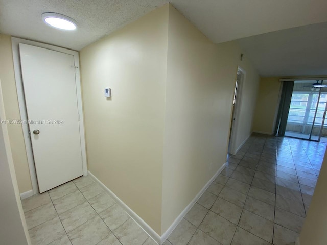 6071 NW 61st Ave Unit 107, Tamarac, FL 33319 - corridor with light tile patterned flooring, baseboards, and a textured ceiling